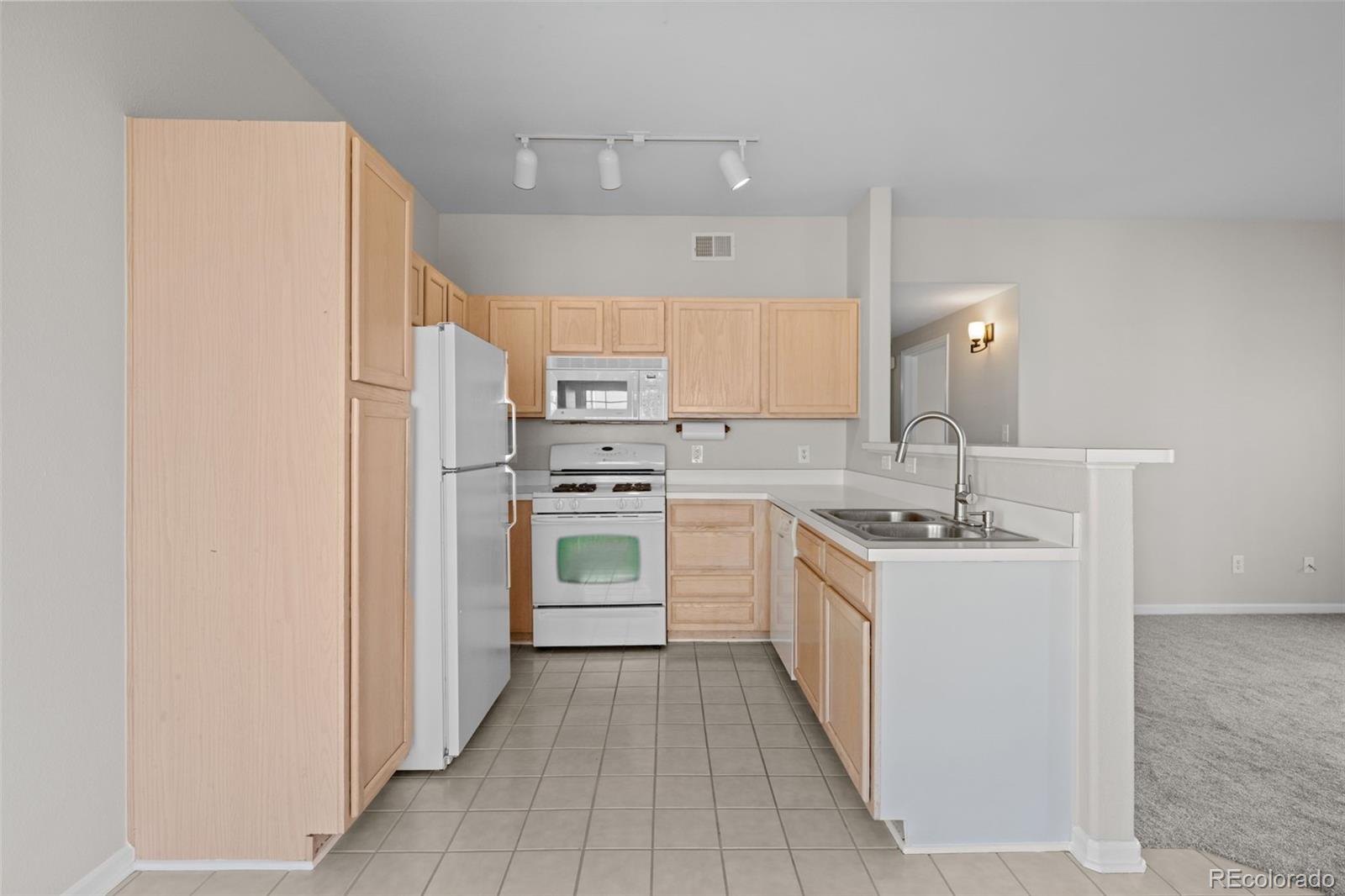 8389 Pebble Creek Way, Unit 101 Highlands Ranch, CO 80126 - Photo 6 of 44 a kitchen with white cabinets and white appliances