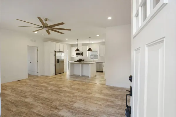 a kitchen with stainless steel appliances granite countertop a sink a stove a refrigerator and island with wooden floor