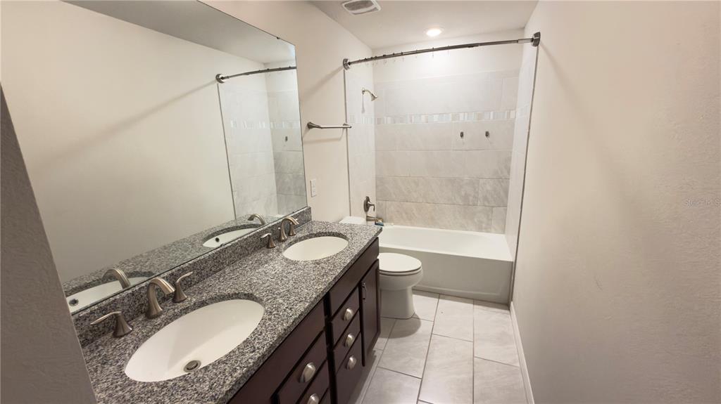 7360 Pool Compass Loop Wesley Chapel, FL 33545 - Photo 42 of 54 a bathroom with a granite countertop sink a mirror and a bathtub