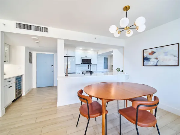 a dining room with wooden floor a chandelier a wooden table and chairs