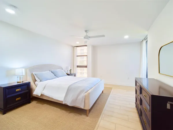 a spacious bedroom with a bed a dresser and a chandelier