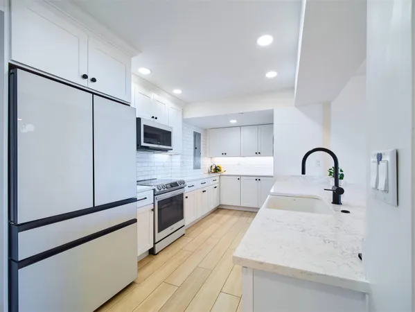 a kitchen with stainless steel appliances a refrigerator sink and white cabinets