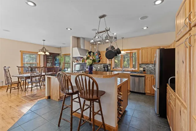 a kitchen with kitchen island granite countertop a table chairs sink and cabinets