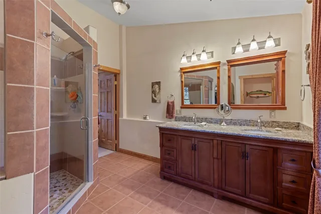a bathroom with a granite countertop sink a mirror and a shower