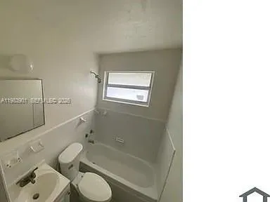 a bathroom with a granite countertop toilet sink and mirror