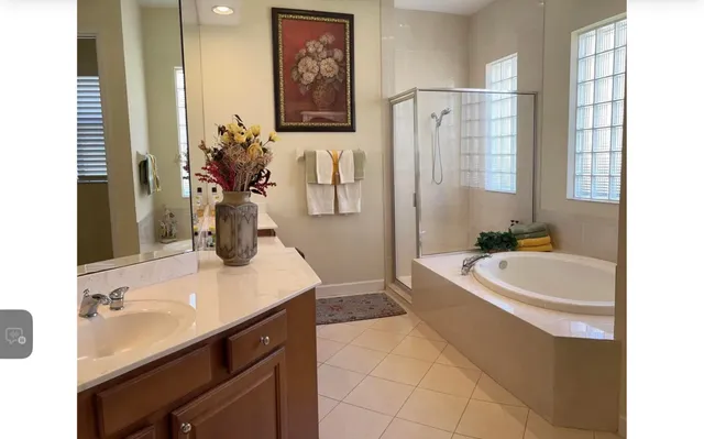a spacious bathroom with a double vanity sink a large mirror a bathtub and shower