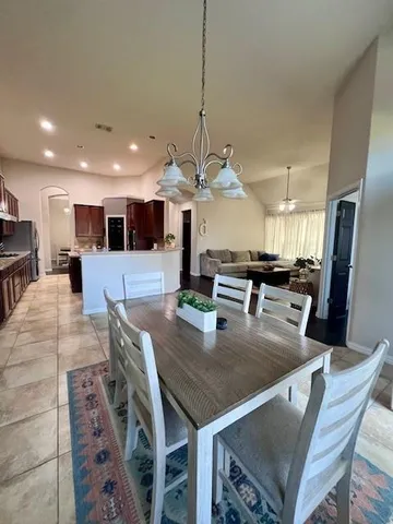 a dining room with stainless steel appliances kitchen island granite countertop a table chairs and a refrigerator