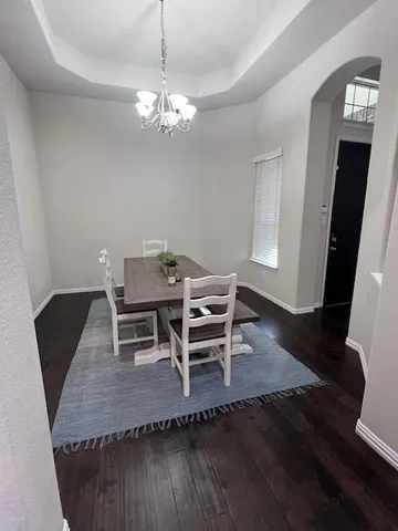 a dining room with wooden floor a chandelier a wooden table and chairs