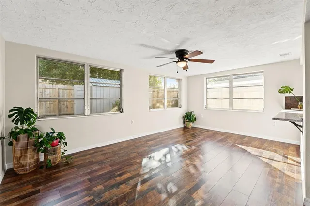 a view of empty room with wooden floor and fan
