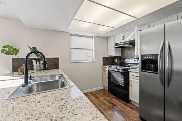 a kitchen with stainless steel appliances granite countertop a sink stove and refrigerator
