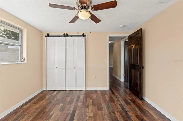 an empty room with wooden floor closet and windows