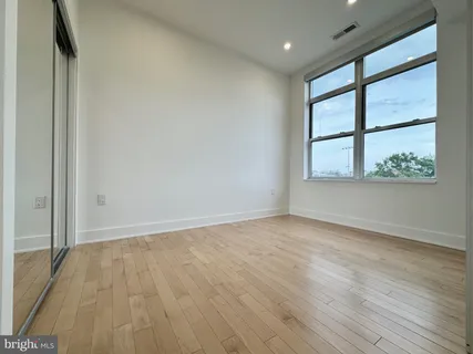 a view of an empty room with wooden floor and a bathroom