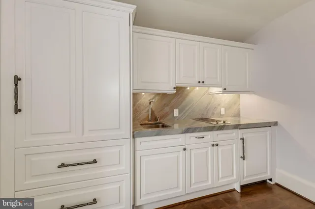 a kitchen with white cabinets and sink