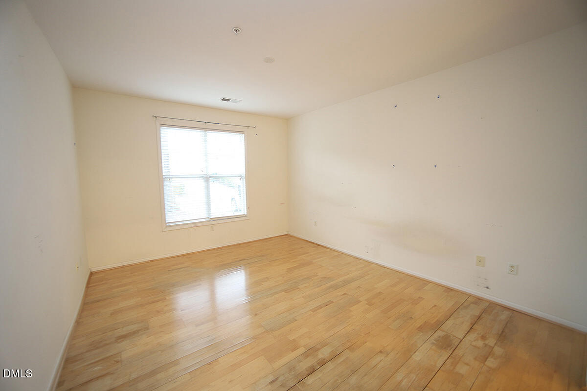 3161 Hemlock Forest Circle, Unit 101 Raleigh, NC 27612 - Photo 13 of 21 an empty room with wooden floor and windows