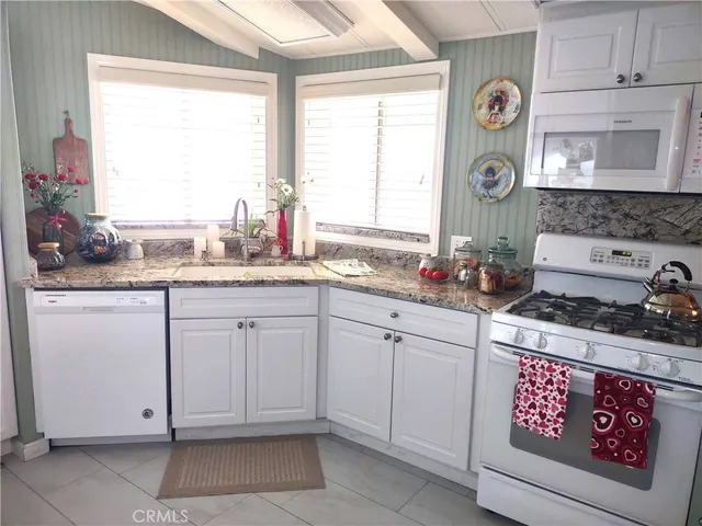 a kitchen with granite countertop cabinets a stove a sink and a window