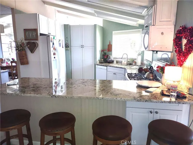 a kitchen with stainless steel appliances granite countertop a table chairs and a refrigerator