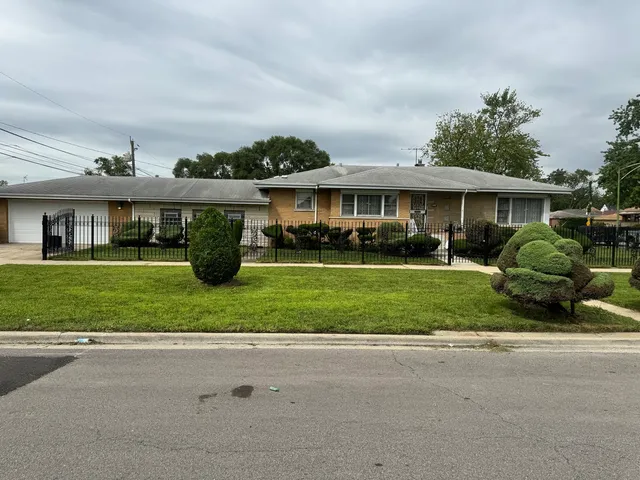 a front view of a house with a garden and trees