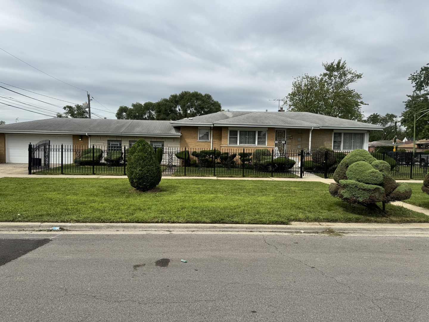 a front view of a house with a garden and trees
