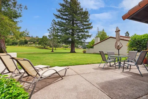 a view of a chairs and table in patio next to a yard