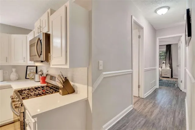 a kitchen with white cabinets and wooden floor