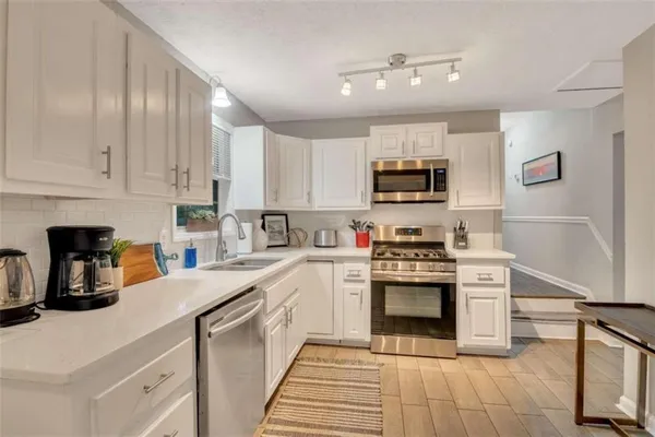 a kitchen with stainless steel appliances granite countertop a stove and white cabinets