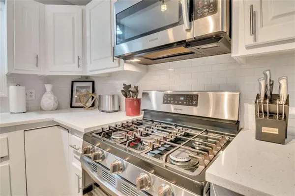 a kitchen with a stove and white cabinets