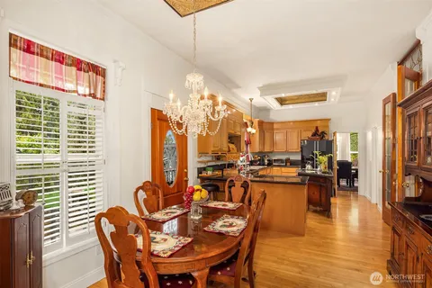 a view of a dining room with furniture one side kitchen view and wooden floor