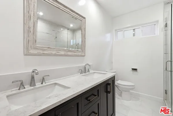 a bathroom with a granite countertop sink a toilet and a mirror