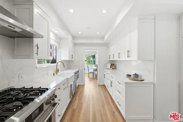 a kitchen with white cabinets stove and sink