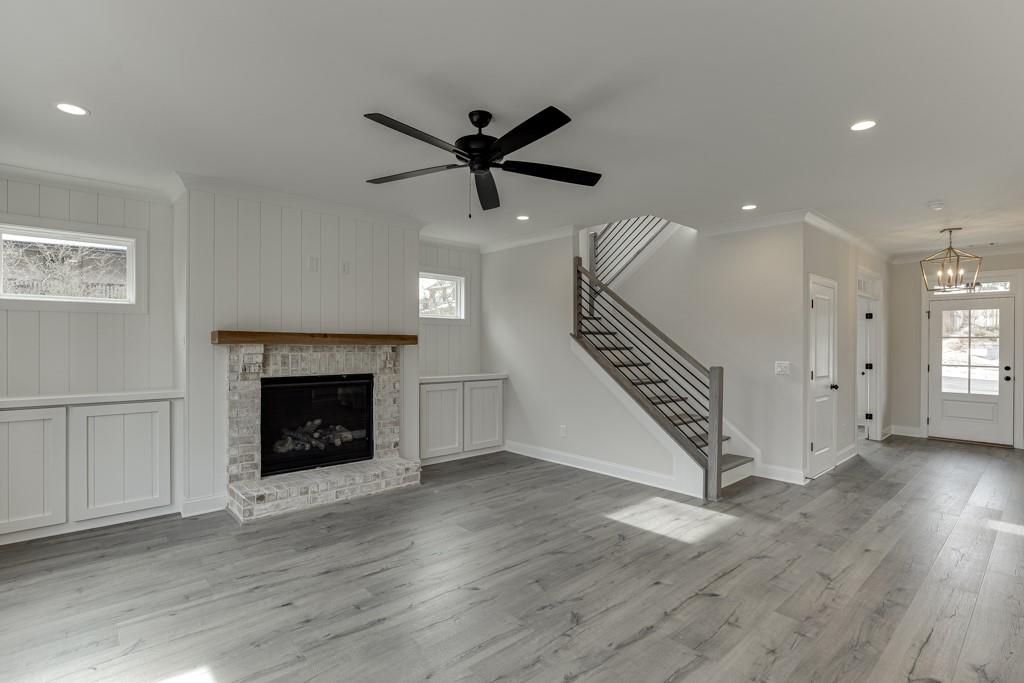 173 Swimming Pool Road Buford, GA 30518 - Photo 13 of 68 a view of an empty room with wooden floor a ceiling fan and a fireplace