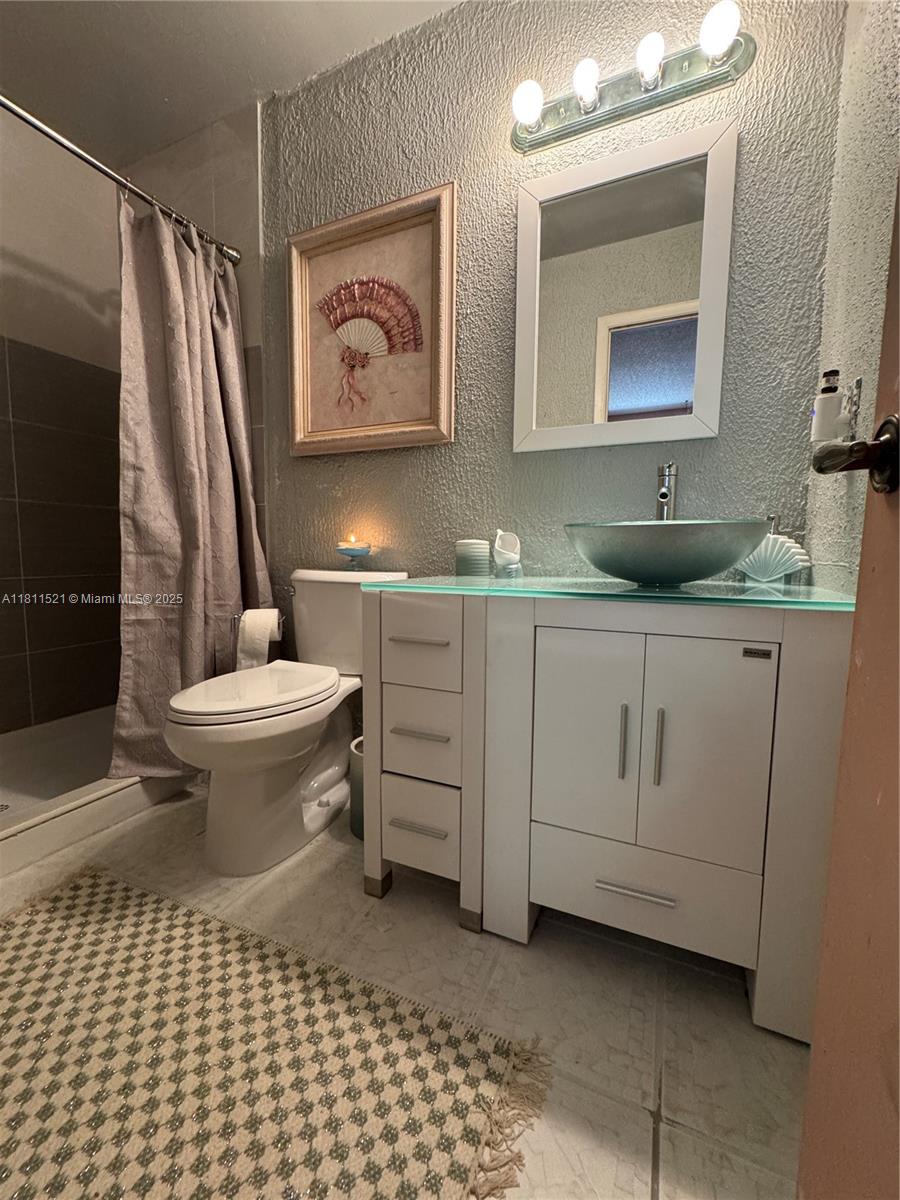 10428 Northwest 3rd Street Pembroke Pines, FL 33026 - Photo 17 of 30 a bathroom with a toilet a sink a mirror a vanity and shower