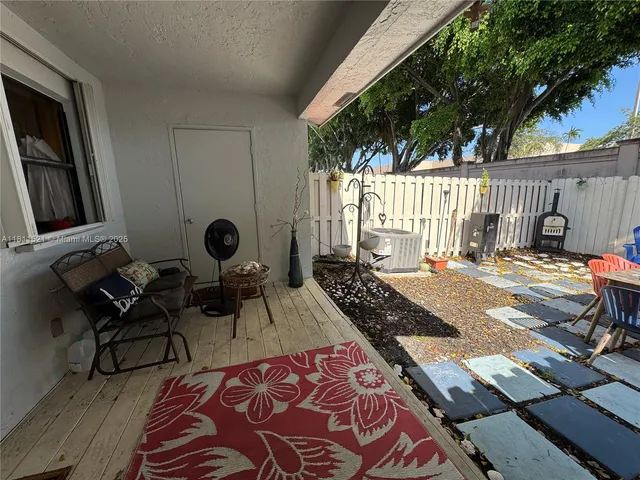 a view of a patio with table and chairs with wooden floor and fence