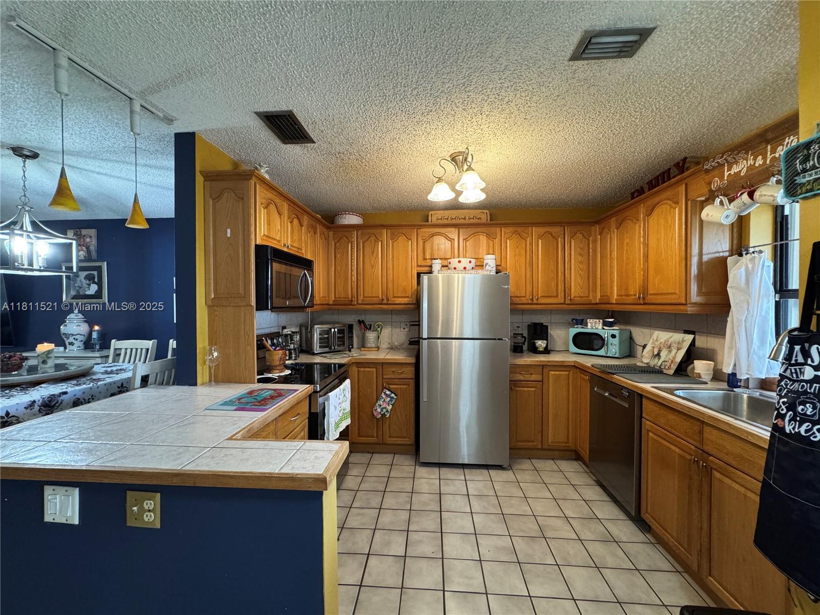 10428 Northwest 3rd Street Pembroke Pines, FL 33026 - Photo 5 of 30 a kitchen with refrigerator a sink and chairs
