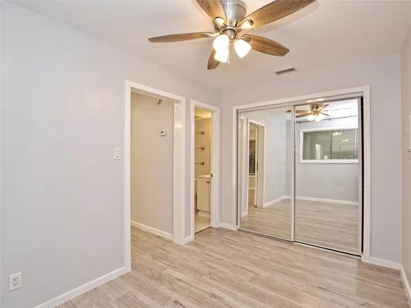 an empty room with wooden floor fan and windows