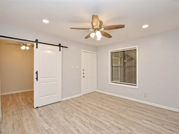 a view of an empty room with a window and wooden floor