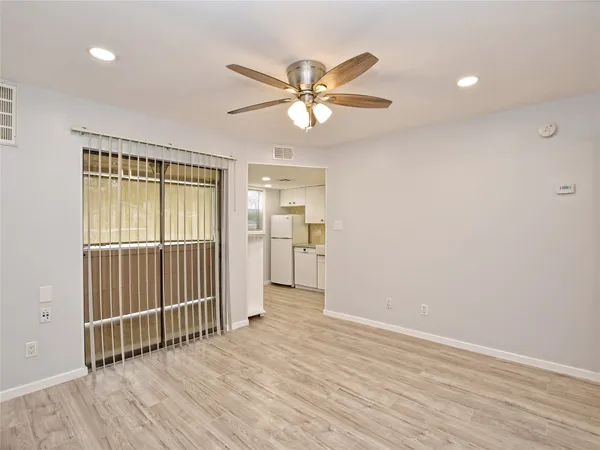 an empty room with wooden floor fan and windows