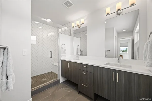 a bathroom with a double vanity sink mirror and shower