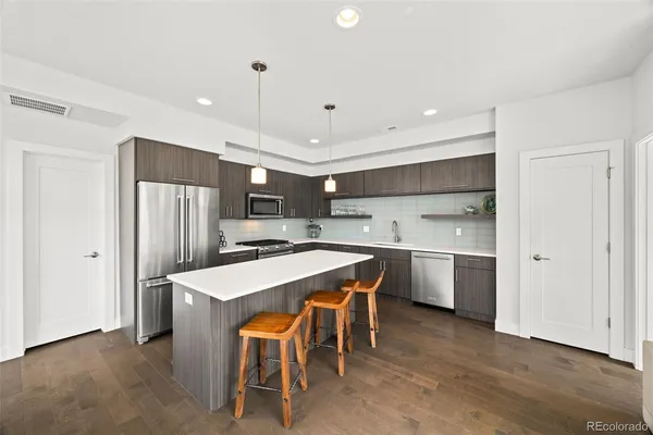 a kitchen with a table a refrigerator a sink and cabinets