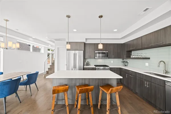 a kitchen with stainless steel appliances kitchen island granite countertop a table chairs sink and cabinets