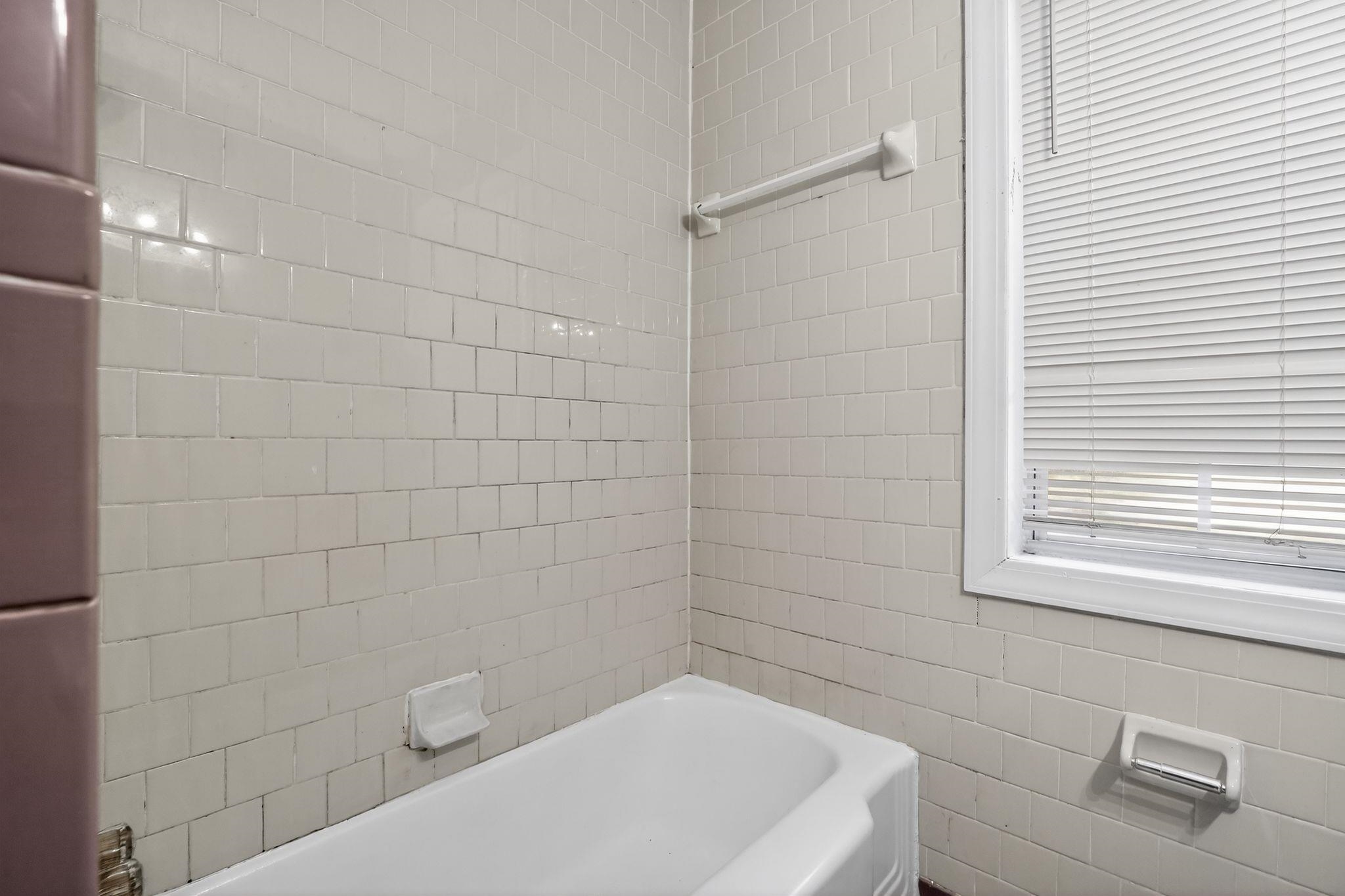4199 Auburn Road Memphis, TN 38116 - Photo 26 of 32 White ceramic tile surround with a white bathtub and window with blinds