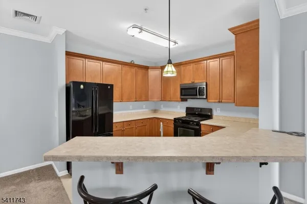 a kitchen with stainless steel appliances a kitchen island a stove a refrigerator a dining table and chairs with wooden floor