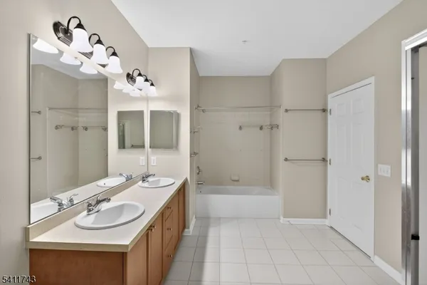 a bathroom with a sink double vanity granite tub shower and a mirror