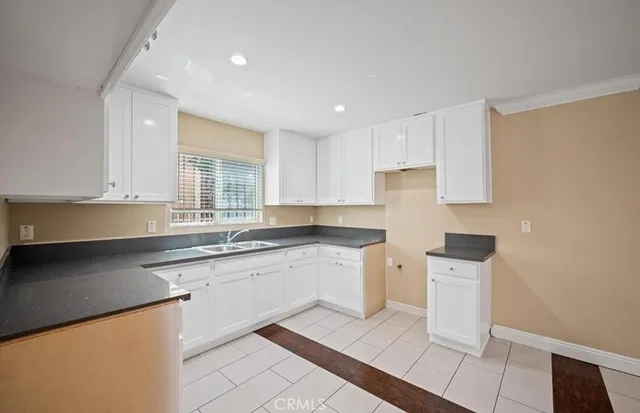 a kitchen with granite countertop white cabinets white appliances sink and a counter top