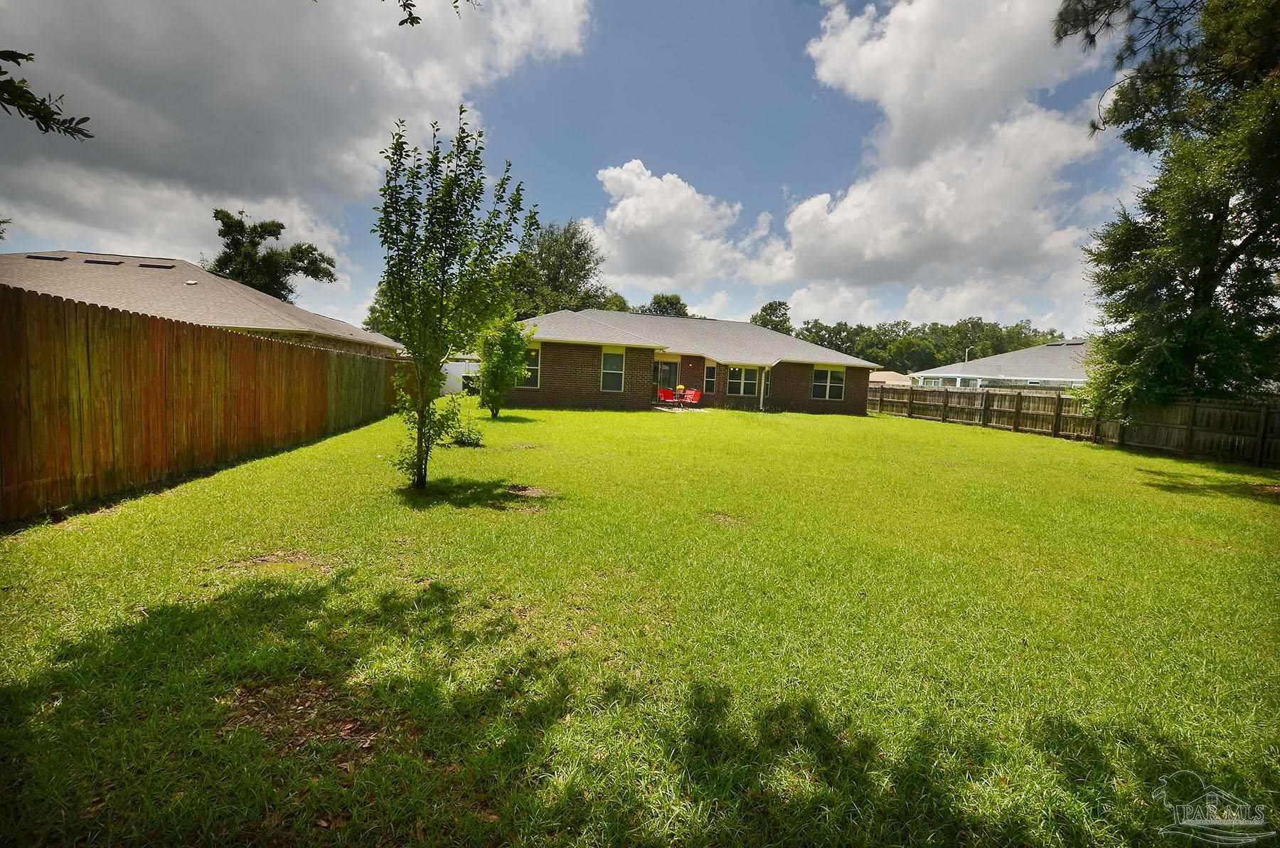 5709 Mill Stream Way Pace, FL 32571 - Photo 43 of 48 a swimming pool with plants and large trees in the background