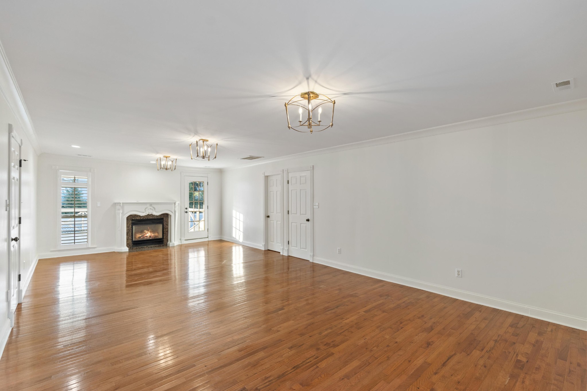 8421 Pedigo Road Powell, TN 37849 - Photo 24 of 57 an empty room with wooden floor fireplace and chandelier fans