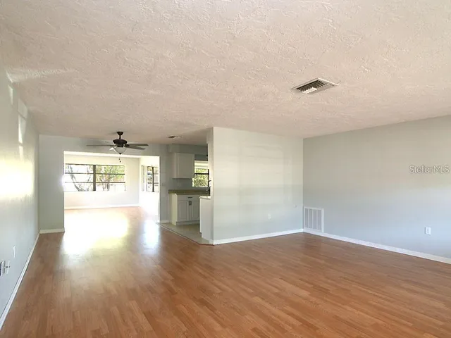 a view of empty room with wooden floor and fan