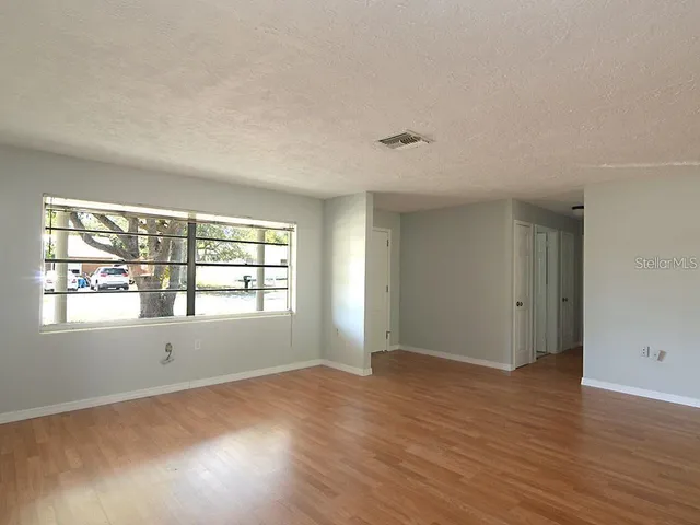 an empty room with wooden floor and windows
