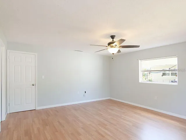 an empty room with a window and a ceiling fan