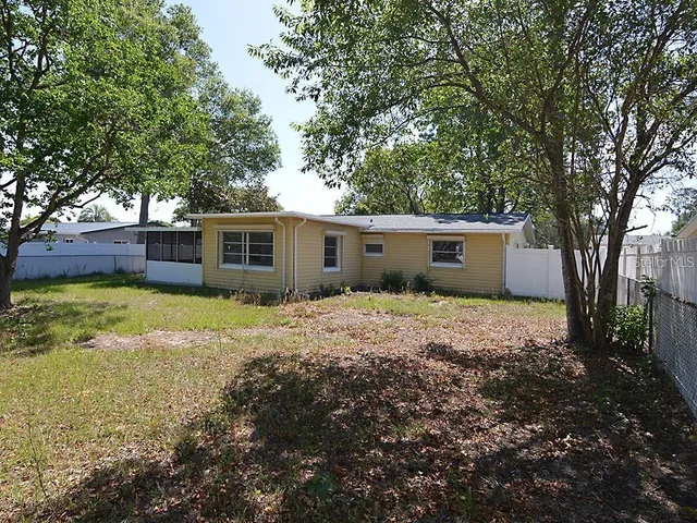 a view of a house with a yard and large tree