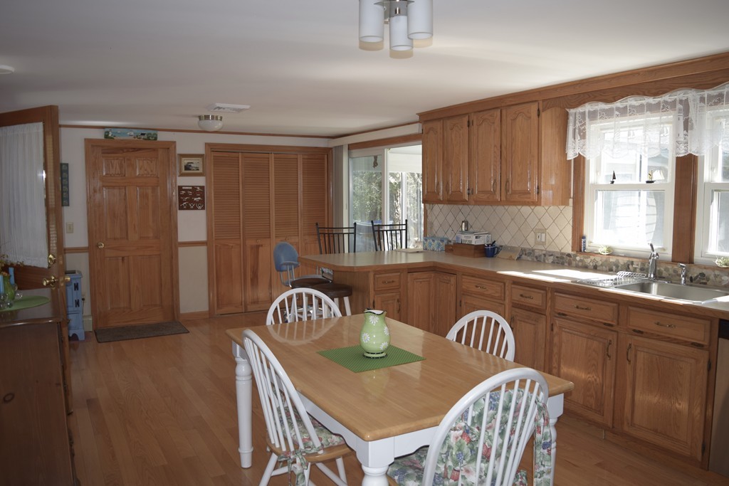 106 Williston Road Bourne, MA 02562 - Photo 3 of 9 a kitchen with a refrigerator a sink a stove a dining table and chairs